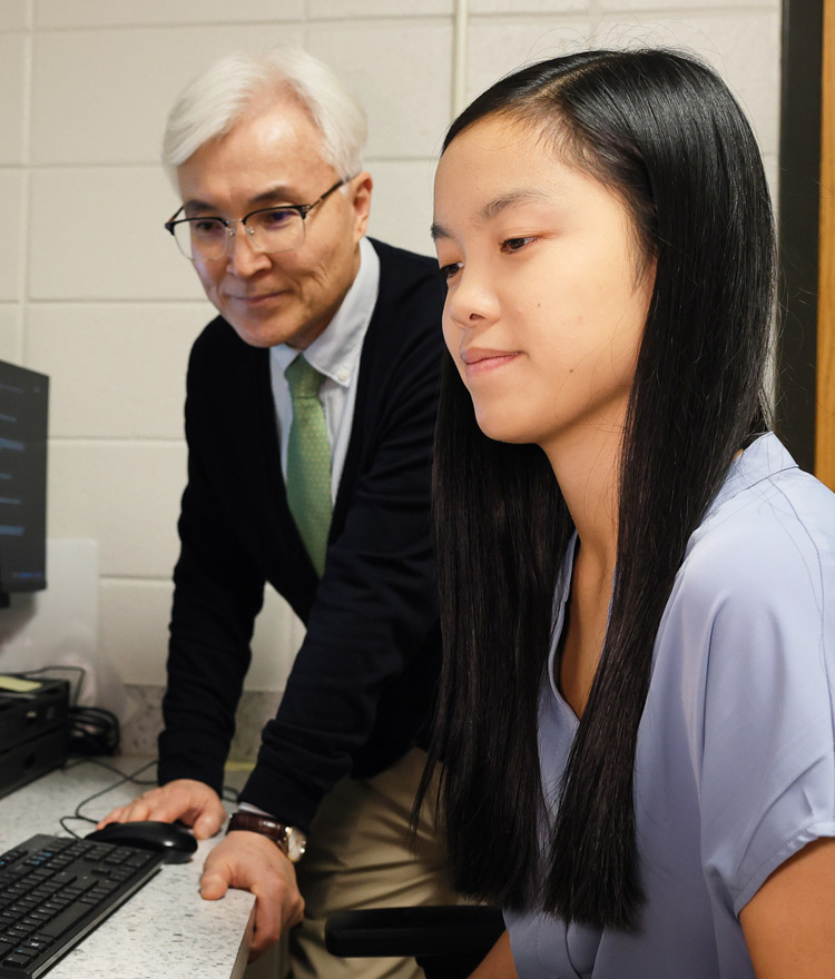 Faculty member looks over a student's shoulder